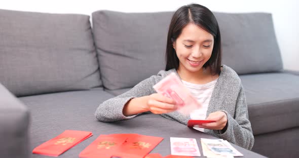 Woman putting banknote into red packet