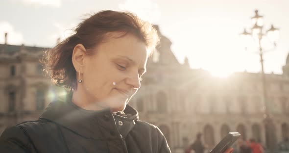 Woman Looks and Taking Picture with Phone Camera in Sunny Day Outside in Paris France Europe. Midle