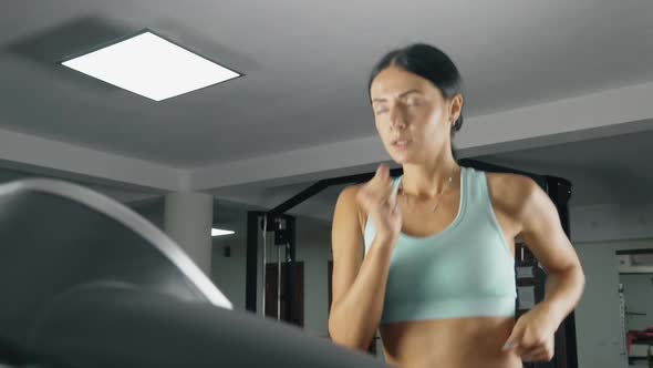 Athletic Woman is Running on a Treadmill at the Gym