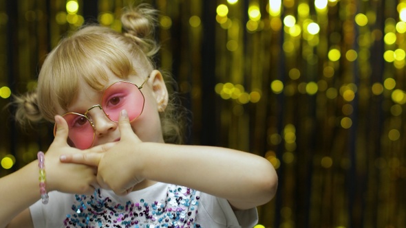 Child Kid Dancing, Waving Hands, Fooling Around. Girl Posing on Background with Foil Curtain