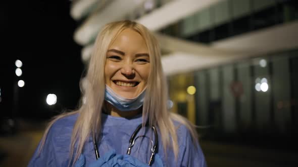 Happy Female Surgeon Smiles Near Hospital During Night Shift