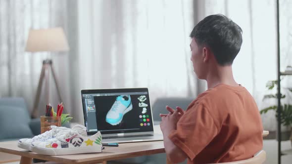 Asian Boy Footwear Designer Stretching After Designing Shoe On A Laptop At Home