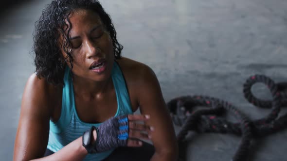 African american woman resting after battling ropes in an empty urban building