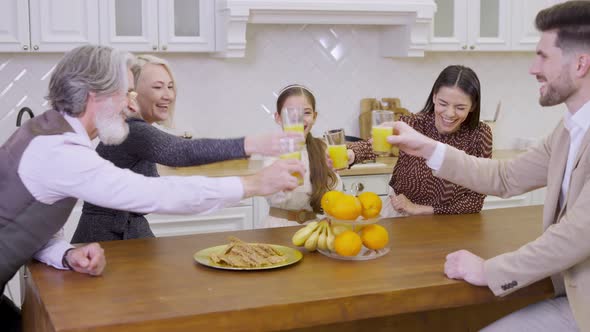 Family Clinking Glasses with Orange Juice Celebrating Together Birthday of Cute Little Girl