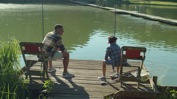 Excited School Age Son and Black Dad Catching Fish with Rod on Lake