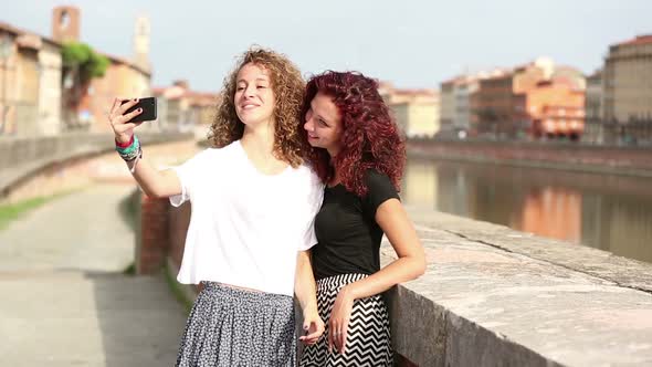 Two happy girls taking a selfie with cityscape on background