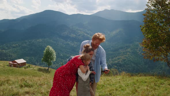 Friendly Family Using Smartphone in Mountains