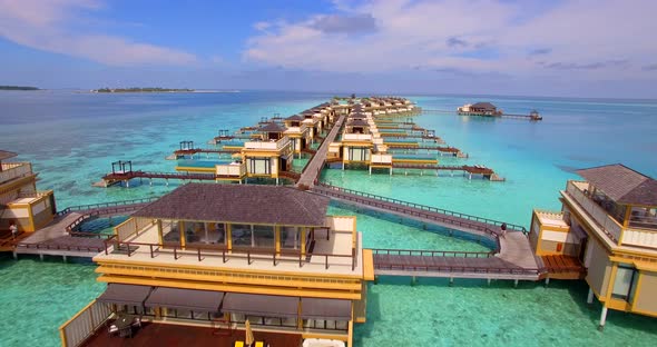 Aerial drone view of scenic tropical island and resort hotel with overwater bungalows in Maldives.