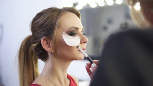 Makeup Artist Applying Eyeshadow on Eyelid Using Makeup Brush and Protecting Sking with White