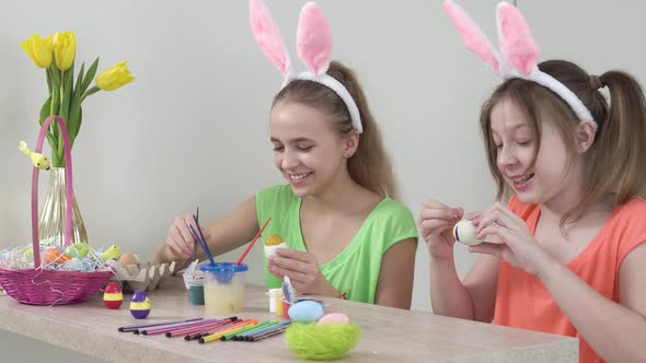 Girls are Decorating Easter Eggs and Laughing with Rabbit Ears on Their Heads