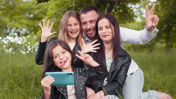 Positive Family Sitting Together on Soft Plaid Utdoors and Taking Selfie on