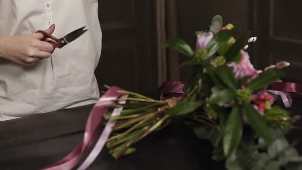 A Girl in a White Shirt Cuts Long Pink Ribbons and Purple Broad Ribbons of Guipure to Decorate a