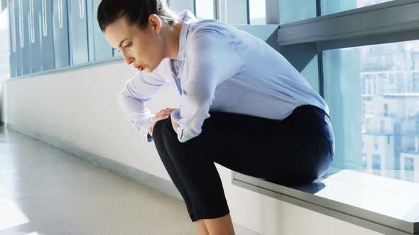 Tense female business executive sitting with hand on forehead