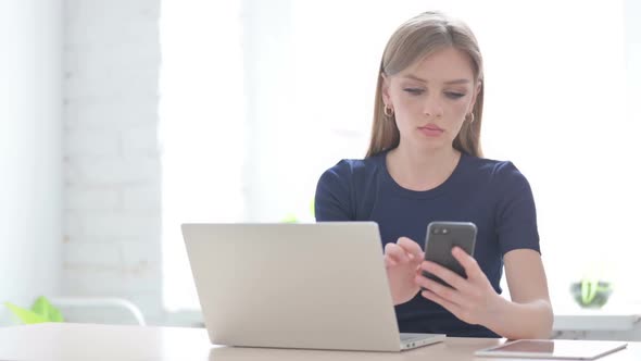 Woman Using Smartphone While Using Laptop