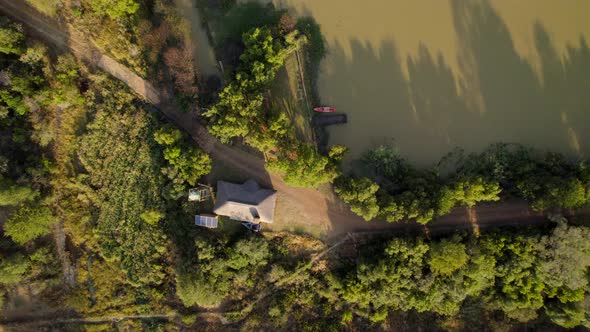 Aerial top down view of isolated independent rural house with solar panel close to a lake at sunset.