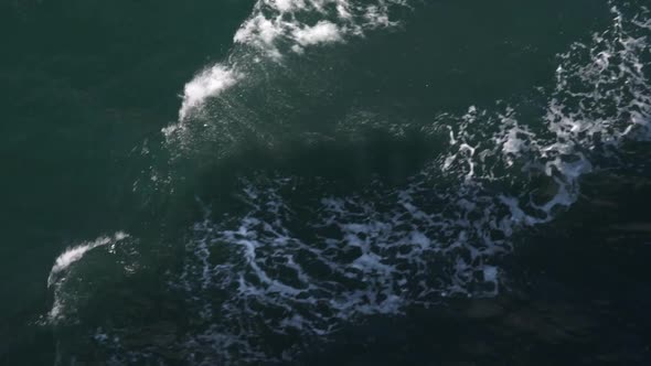 Dark turquoise water surface with waves of a ship and its shawos in it. Close-up