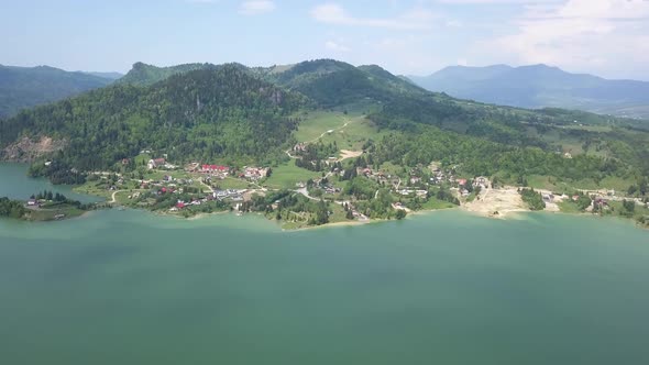 Aerial Panning shot of Lake with Green Forests on a sunny day