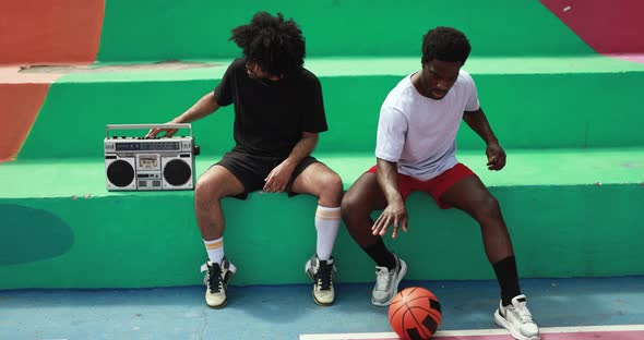 Young african people listening music from vintage boombox stereo outdoor after basketball match