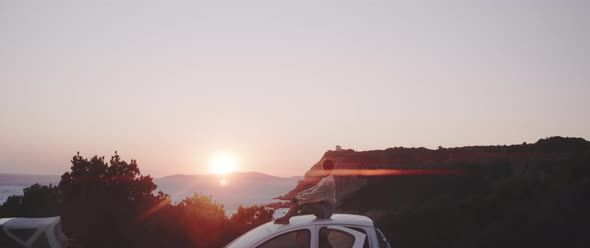 Beautiful summer landscape view with a girl sitting on the roof of her car