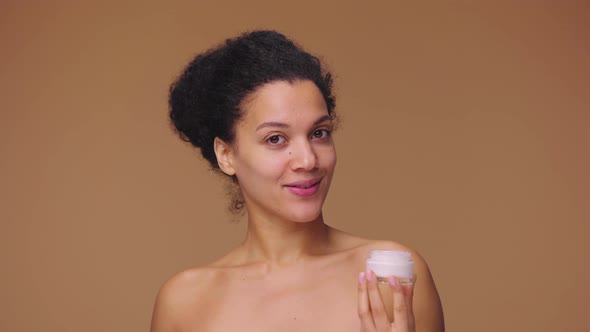 Beauty Portrait of Young African American Woman Smears Face Care Cream on Tip of Her Nose and Smiles