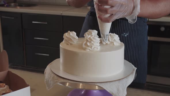 Woman Chef Decorating White Handmade Cake with Cream on Top