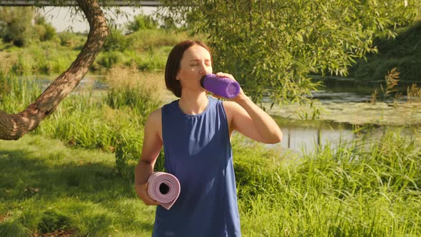 Beautiful young woman drinking water from plastic bottle.