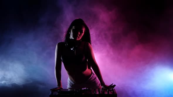 Girl DJ Playing on Turntables, Behind Her Pink Blue Lights. Slow Motion