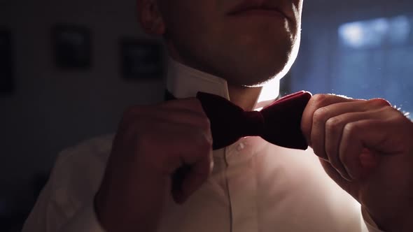 Groom Adjusts Bow Tie Preparing to Go to the Bride Businessman in White Shirt Wedding Day