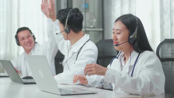 Successful of Three Asian Doctors With Stethoscopes In Headsets Working As Call Centre Agents