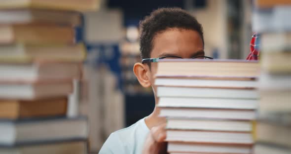 Close Up of African Kid Feeling Shocked When Librarian Putting Large Stack of Book on Table