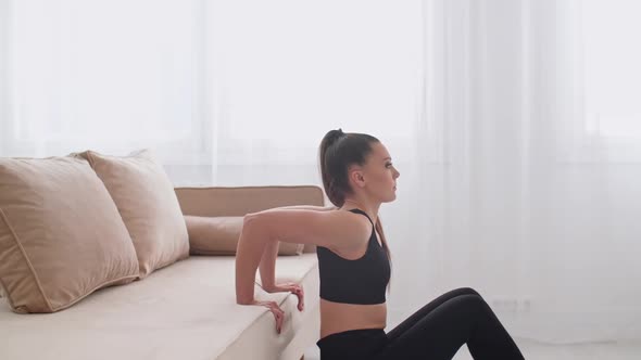 Sporty Young Woman Doing Workout Exercises Using Couch at Home