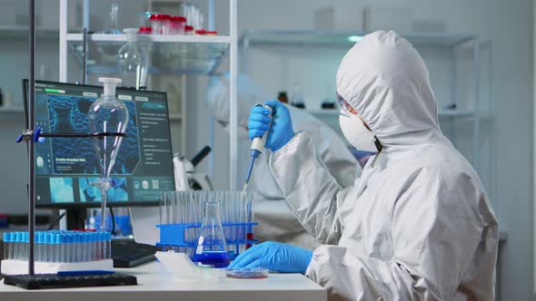 Chemist Wearing Ppe Suit Putting Liquid in Test Tube with Micropipette