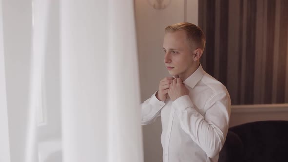 Stylish Man in Jacket Fastens Buttons Buttoning White Shirt Preparing to Go Out Near Window