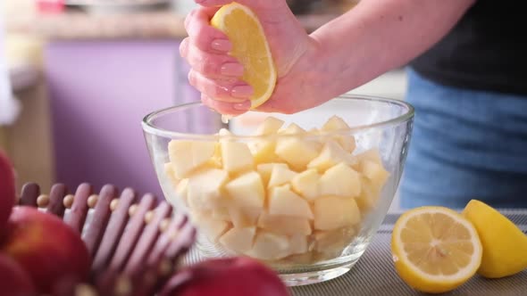 Apple Pie Preparation Series  Woman Squeezing Lemon Juice Into Glass Bowl with Chopped Apples