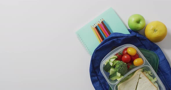 Video of healthy packed lunch of fruit and vegetables, with coloured pencils on schoolbag