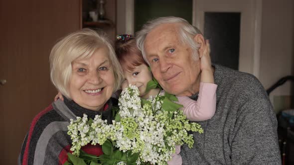 Granddaughter Embraces Senior Smiling Grandfather with Grandmother at Home