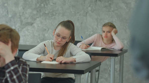 Students in school uniform taking exam at desk in a classroom