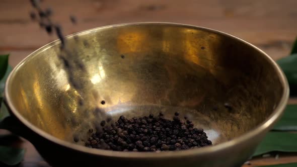 Whole and Ground Black Peppercorns on Old Wooden Table Dropped Pour in Bowl