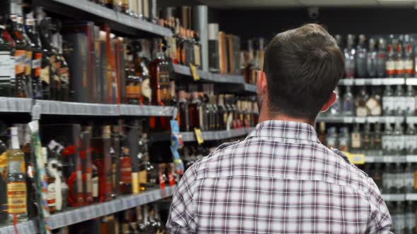 Rearview Shot of a Man Examining Wine on the Shelves at the Supermarket