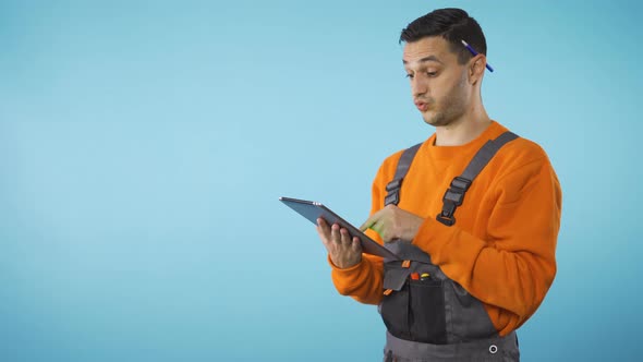 Construction Worker with Pen Behind Ear Taking Notes on Tablet, Copyspace