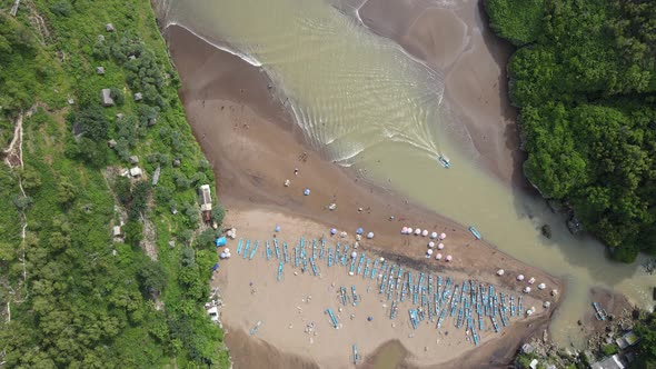 Aerial top view of Baron Beach in Gunung Kidul, Indonesia with lighthouse and traditional boat.