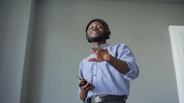 an AfricanAmerican Man Listens to Music with Headphones and Dances