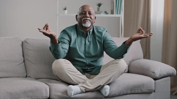 Happy Elderly African American Man Sit on Sofa in Lotus Position with Folded Fingers Grandpa is