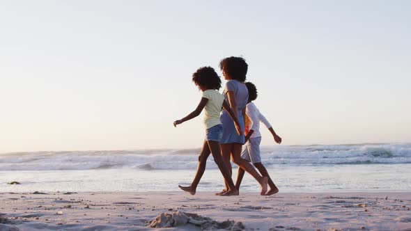 African american mother son and daughter having fun walking together on the beach