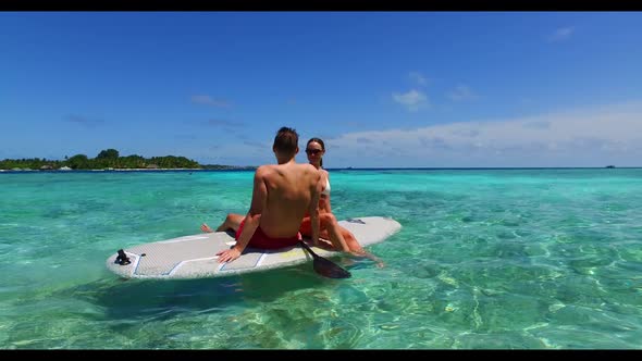 Family of two posing on idyllic seashore beach lifestyle by turquoise water and white sandy backgrou