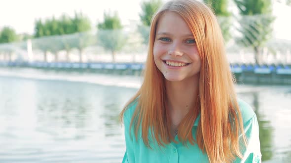 Portrait of a young beautiful woman with red hair in a park in the spring