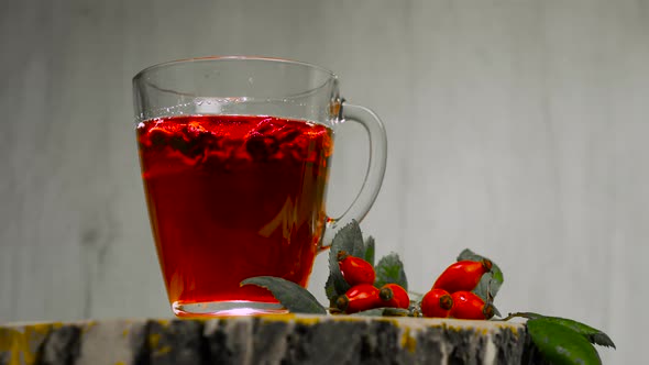 Tincture Of Herbs And Red Berries In A Cup, Tea From Medicinal Rose Hips On A Wooden Background