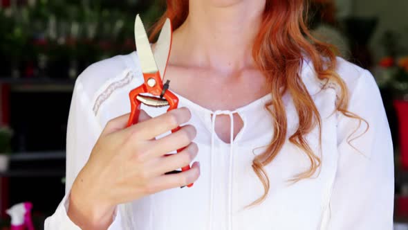 Female florist holding scissor in flower shop