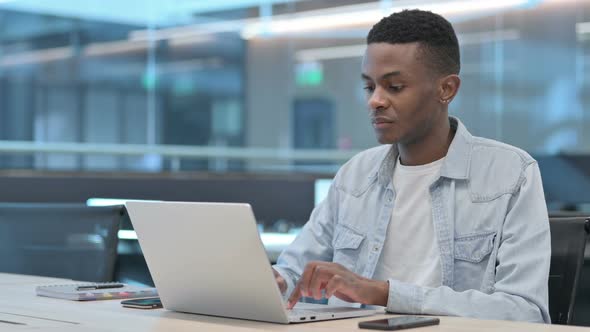 African Man Working on Laptop in Office