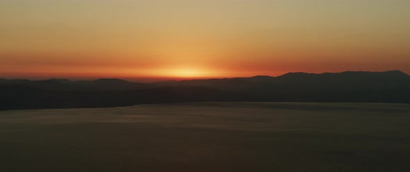 Beautiful landscape with sunset over the big lake and the mountains. Tilting down to up shot. 